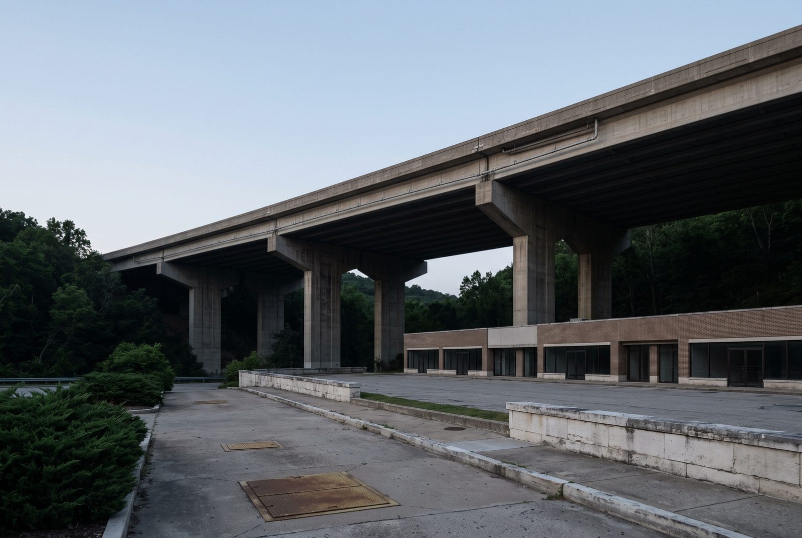 A concrete highway overpass crossing a wooded valley at dusk